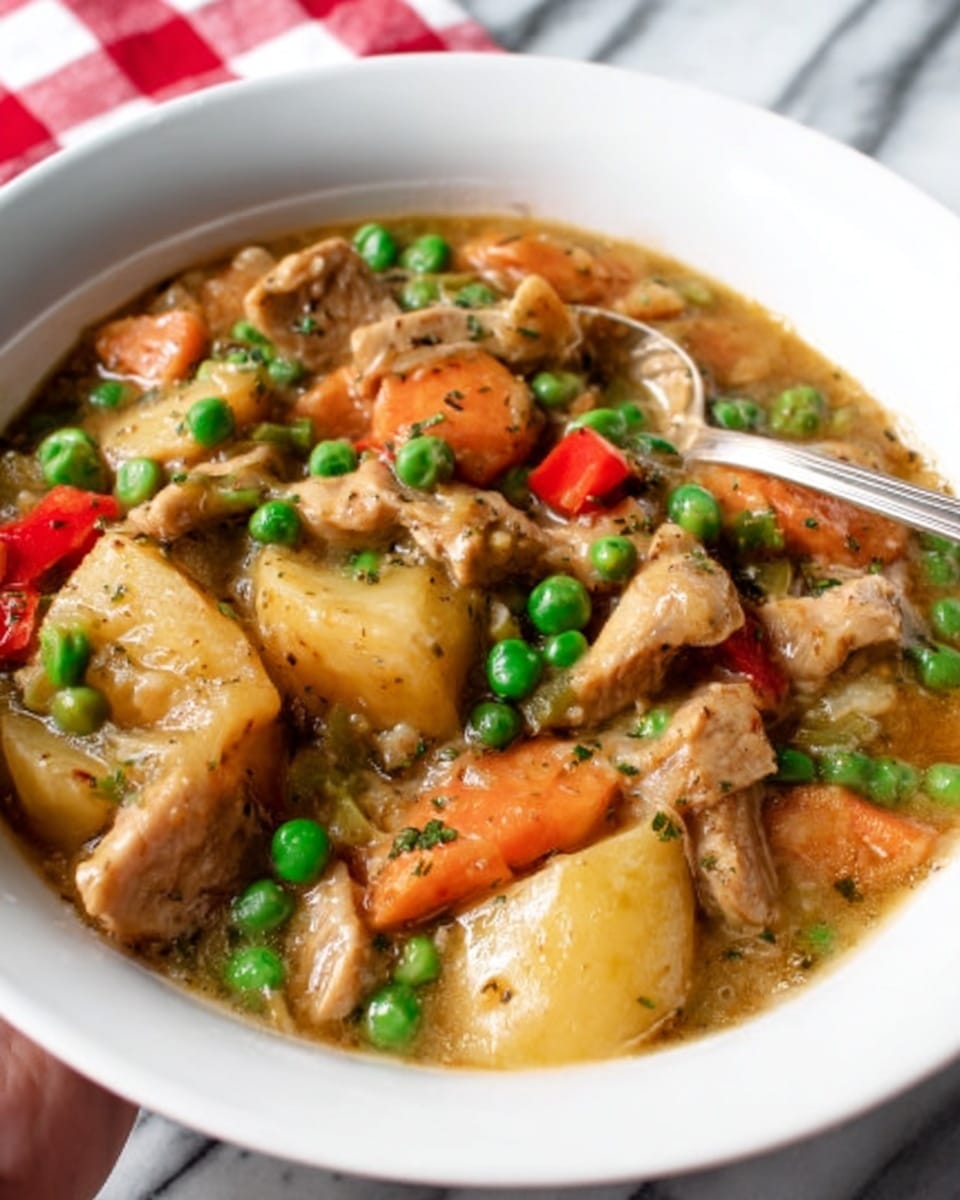 The image shows a close-up of a bowl filled with a chicken and vegetable stew. The stew has thick pieces of light golden browned chicken on the top layer, surrounded by diced yellow potatoes, orange carrot slices, brown mushrooms, and light green celery pieces, all sitting in a golden broth. Scattered bright green parsley leaves are spread throughout, adding a fresh touch. Tiny black pepper specks are visible on top, giving texture. The bowl is white and the background has a white marbled texture. photo taken with an iphone --ar 4:5 --v 7