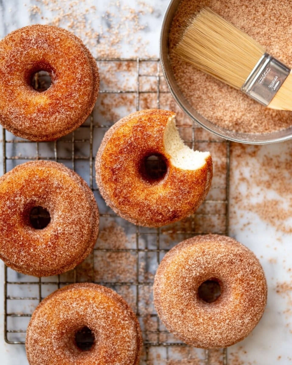 Seven round donuts with a hole in the middle are shown on a wire rack above a white marbled surface. Each donut is covered evenly with a light brown sugar and cinnamon coating, giving them a slightly grainy texture. They have a warm, golden-brown color and look soft on the inside while a little crisp on the outside. The donuts are arranged casually, filling most of the frame. Photo taken with an iphone --ar 4:5 --v 7